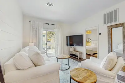 a living room with two white couches and a tv at Pool-view condo with private balcony AC & washer&dryer in Santa Rosa Beach