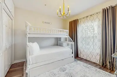 a white bunk bed in a room with a chandelier at Pool-view condo with private balcony AC & washer&dryer in Santa Rosa Beach