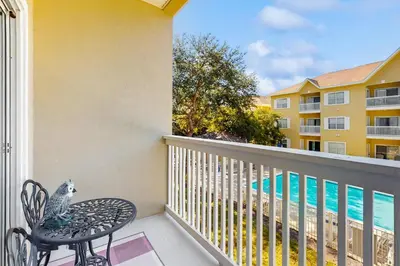a balcony with a table and chair and a swimming pool at Pool-view condo with private balcony AC & washer&dryer in Santa Rosa Beach