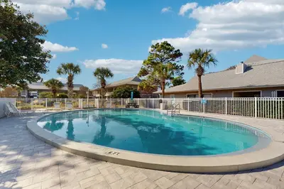 a large swimming pool with a fence and trees at Cozy coastal condo dog friendly with shared pool and close to beach in Santa Rosa Beach
