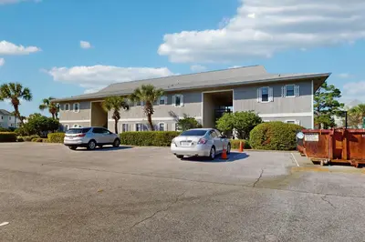 two cars parked in a parking lot in front of a building at Cozy coastal condo dog friendly with shared pool and close to beach in Santa Rosa Beach