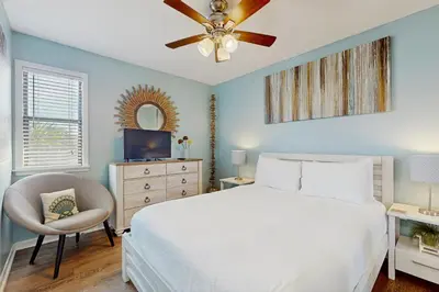 a bedroom with a white bed and a ceiling fan at Cozy coastal condo dog friendly with shared pool and close to beach in Santa Rosa Beach