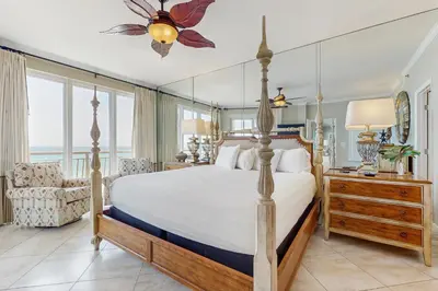 a bedroom with a large bed and a chair at Open-concept beachfront home with balcony lagoon pool beach access pickleball in Seacrest