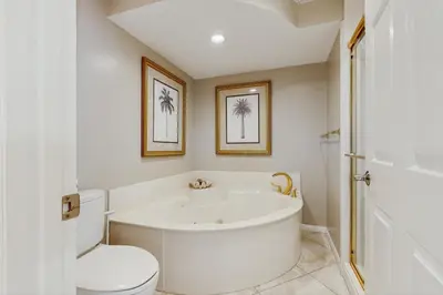 a white bathroom with a tub and a toilet at Open-concept beachfront home with balcony lagoon pool beach access pickleball in Seacrest