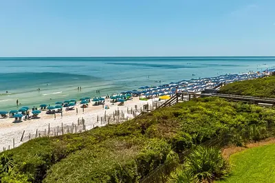 a beach with umbrellas and the ocean at Open-concept beachfront home with balcony lagoon pool beach access pickleball in Seacrest