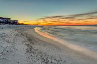 a view of a beach with a sunset in the background at Open-concept beachfront home with balcony lagoon pool beach access pickleball in Seacrest