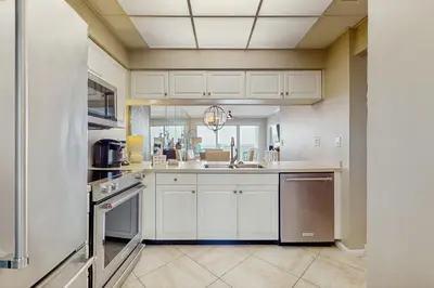 a kitchen with white cabinets and stainless steel appliances at Open-concept beachfront home with balcony lagoon pool beach access pickleball in Seacrest
