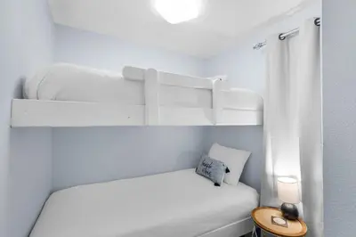 a small white bedroom with a bunk bed at Lovely waterfront condo with balcony pool hot tub & pickleball in Santa Rosa Beach