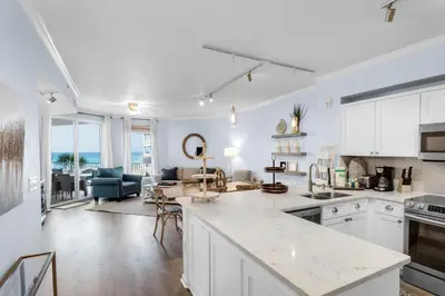 a kitchen with white cabinets and a living room at Lovely waterfront condo with balcony pool hot tub & pickleball in Santa Rosa Beach