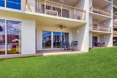 a house with a patio with chairs and tables at Beach haven with patio lagoon pool hot tub & pickleball - walk to beach in Seacrest