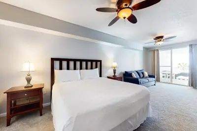 a bedroom with a white bed and a blue couch at Lovely condo with pool hot tub ocean views & pickleball in Santa Rosa Beach