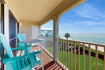 a balcony with chairs and a table and the ocean at Ideally located beachfront home with balcony washer&dryer AC & amazing views in Seacrest