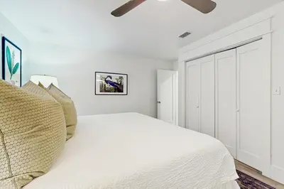 a white bedroom with a bed and a ceiling fan at Ideally located beachfront home with balcony washer&dryer AC & amazing views in Seacrest
