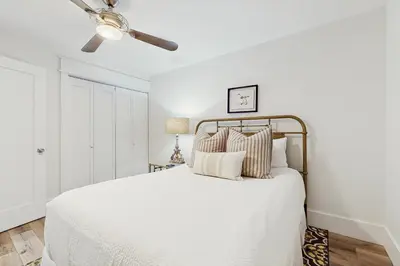 a bedroom with a white bed with a ceiling fan at Ideally located beachfront home with balcony washer&dryer AC & amazing views in Seacrest