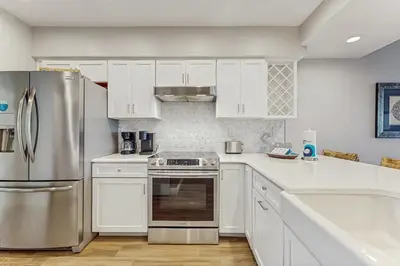 a kitchen with white cabinets and a stainless steel refrigerator at Water-view condo with pool hot tub & pickleball in Rosemary Beach