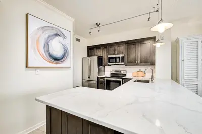 a kitchen with a white counter top and wooden cabinets at Chic first-floor condo with Gulf & pool view & pickleball - steps to beach in Santa Rosa Beach