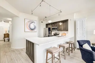 a kitchen with a counter and stools at Chic first-floor condo with Gulf & pool view & pickleball - steps to beach in Santa Rosa Beach