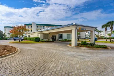 a building with a parking lot in front of it at Chic first-floor condo with Gulf & pool view & pickleball - steps to beach in Santa Rosa Beach