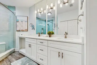 a white bathroom with two sinks and a mirror at Luxe Beachfront Resort Condo with Private Beach Access & Top Amenities in Santa Rosa Beach