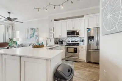 a kitchen with white cabinets and stainless steel appliances at Luxe Beachfront Resort Condo with Private Beach Access & Top Amenities in Santa Rosa Beach