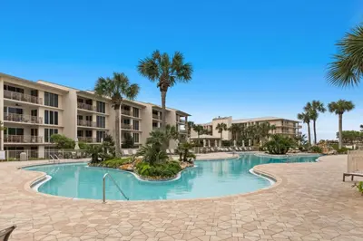 a swimming pool at a resort with palm trees and buildings at Gulf front condo with beach access pool hot tub tennis & pickleball in Seacrest