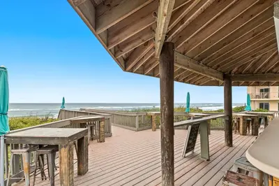 a wooden deck with tables and benches on the beach at Gulf front condo with beach access pool hot tub tennis & pickleball in Seacrest