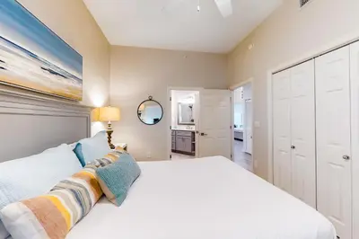 a bedroom with a white bed and a mirror at Stunning 4th-floor condo with pool tennis pickleball ocean & beach view in Santa Rosa Beach