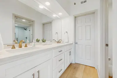 a white bathroom with two sinks and a large mirror at 2nd-floor condo with beach access pool tennis pickleball hot tub balcony in Seacrest