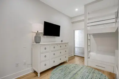 a bedroom with a bed and a tv on a dresser at Luxuriously renovated condo with Gulf views beach access pool & hot tub in Inlet Beach