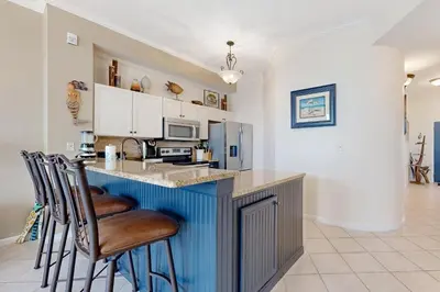 a kitchen with a blue island with bar stools at Beach-view condo with outdoor pool hot tub sauna tennis BBQ & beach access in Santa Rosa Beach