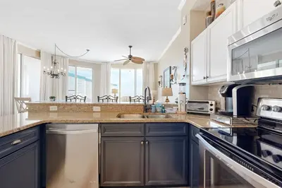 a kitchen with blue cabinets and a sink at Beach-view condo with outdoor pool hot tub sauna tennis BBQ & beach access in Santa Rosa Beach