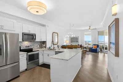 a kitchen with white cabinets and a living room at COMPLETELY UPDATED with beach access pool hot tub tennis pickleball & gym in Santa Rosa Beach