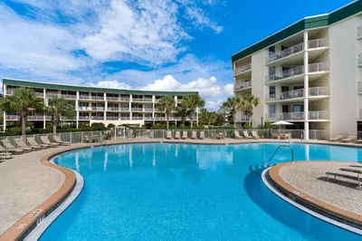 a swimming pool with chairs and a building at COMPLETELY UPDATED with beach access pool hot tub tennis pickleball & gym in Santa Rosa Beach