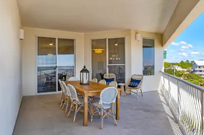 a patio with a wooden table and chairs on a balcony at COMPLETELY UPDATED with beach access pool hot tub tennis pickleball & gym in Santa Rosa Beach