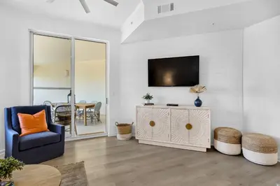 a living room with a tv and a blue chair at COMPLETELY UPDATED with beach access pool hot tub tennis pickleball & gym in Santa Rosa Beach