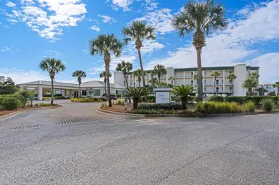 an empty parking lot in front of a building with palm trees at Oceanfront condo with pool hot tub sauna gym bikes tennis - lovely balcony in Santa Rosa Beach