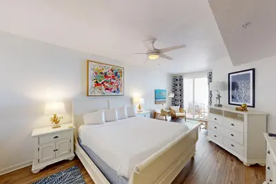 a bedroom with a white bed and a ceiling fan at Coastal condo with beach pool hot tub sauna tennis bikes W&D & central AC in Santa Rosa Beach