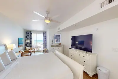 a white bedroom with a bed and a flat screen tv at Coastal condo with beach pool hot tub sauna tennis bikes W&D & central AC in Santa Rosa Beach