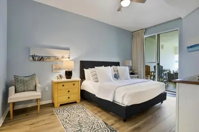 a bedroom with a king sized bed and a chair at Dunes of Seagrove condo with pool hot tub sauna gym & tennis pickleball in Santa Rosa Beach