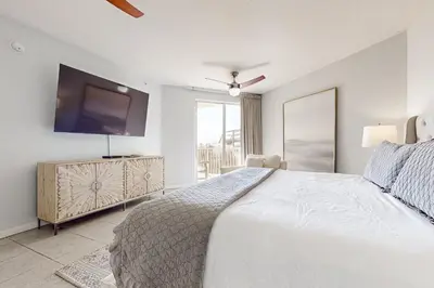 a bedroom with a large bed and a flat screen tv at Ground floor beachfront condo with shared pool and beach access in Santa Rosa Beach