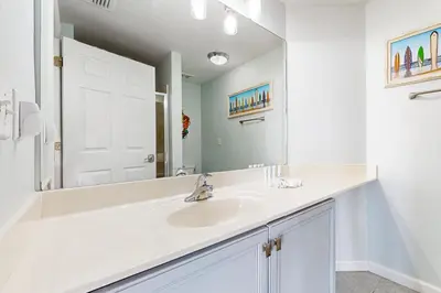 a white bathroom with a sink and a mirror at Ground floor beachfront condo with shared pool and beach access in Santa Rosa Beach