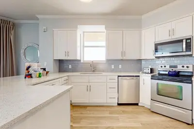 a white kitchen with white cabinets and a sink at Ground floor beachfront condo with shared pool and beach access in Santa Rosa Beach
