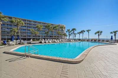 a large swimming pool with palm trees and a building at Dunes of Panama E1702 - Sunrise & Sea Breezes in Panama City Beach