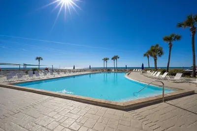 a swimming pool next to a beach with palm trees at Dunes of Panama E1702 - Sunrise & Sea Breezes in Panama City Beach