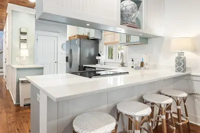 a kitchen with a large white counter with stools at Fin and Tonic - Magnolia Cottages 3 BR, Heated Community Pool, Bikes in Inlet Beach