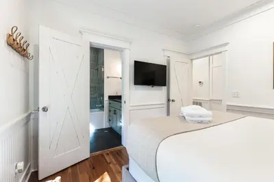 a white bedroom with a bed and a flat screen tv at Fin and Tonic - Magnolia Cottages 3 BR, Heated Community Pool, Bikes in Inlet Beach