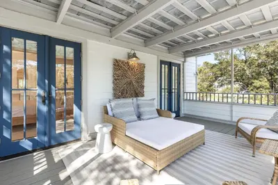 a porch with a bed and wicker chairs at Fin and Tonic - Magnolia Cottages 3 BR, Heated Community Pool, Bikes in Inlet Beach