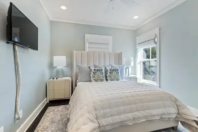 a bedroom with a large bed and a flat screen tv at Seacrest Beach - 3 BR, Bikes, Pool & Beach in Rosemary Beach