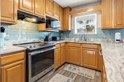 a kitchen with wooden cabinets and a stove top oven at New Kululu EAST - 3 BR Short walk to the beach, heated pool, Sleeps 12 in Santa Rosa Beach