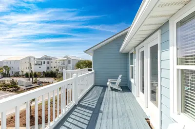 a deck with a chair on a house at New Kululu EAST - 3 BR Short walk to the beach, heated pool, Sleeps 12 in Santa Rosa Beach
